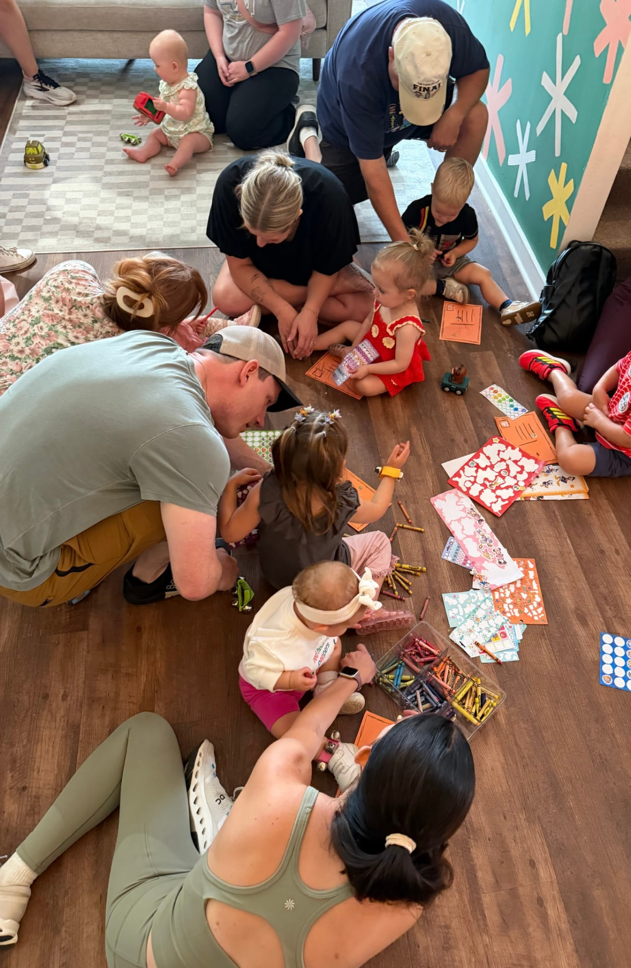 Caregivers and toddlers coloring and playing together on the floor