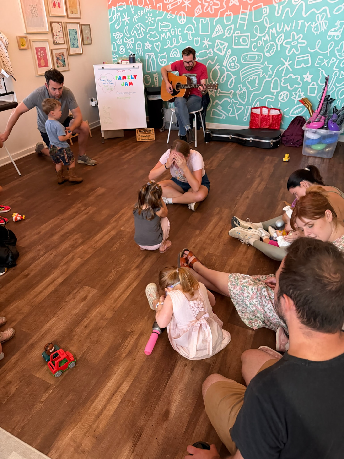 Caregivers and children playing a peek-a-boo song activity during class